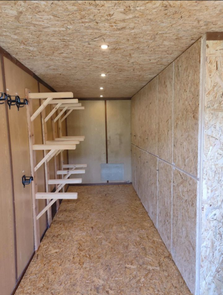 Frisch ausgebaute Sattelkammer mit Sattelhaltern und heller Holzverkleidung